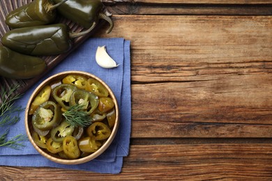 Flat lay composition with pickled green jalapeno peppers on wooden table, space for text