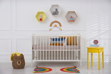 Photo of Cute baby room interior with comfortable crib and toys