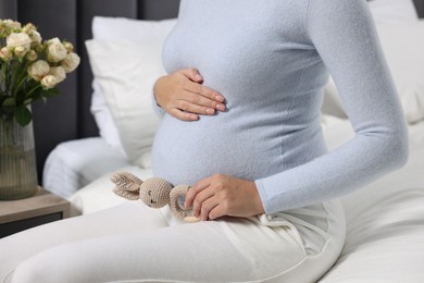 Pregnant woman with bunny toy on bed indoors, closeup