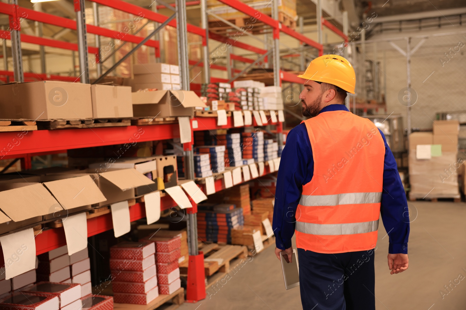 Image of Man with tablet working at warehouse, back view. Logistics center