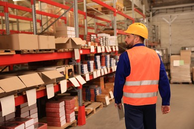 Man with tablet working at warehouse, back view. Logistics center