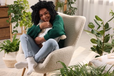 Photo of Happy woman relaxing surrounded by beautiful houseplants at home