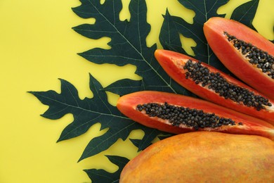 Photo of Fresh ripe cut and whole papaya fruits with leaf on yellow background, flat lay. Space for text