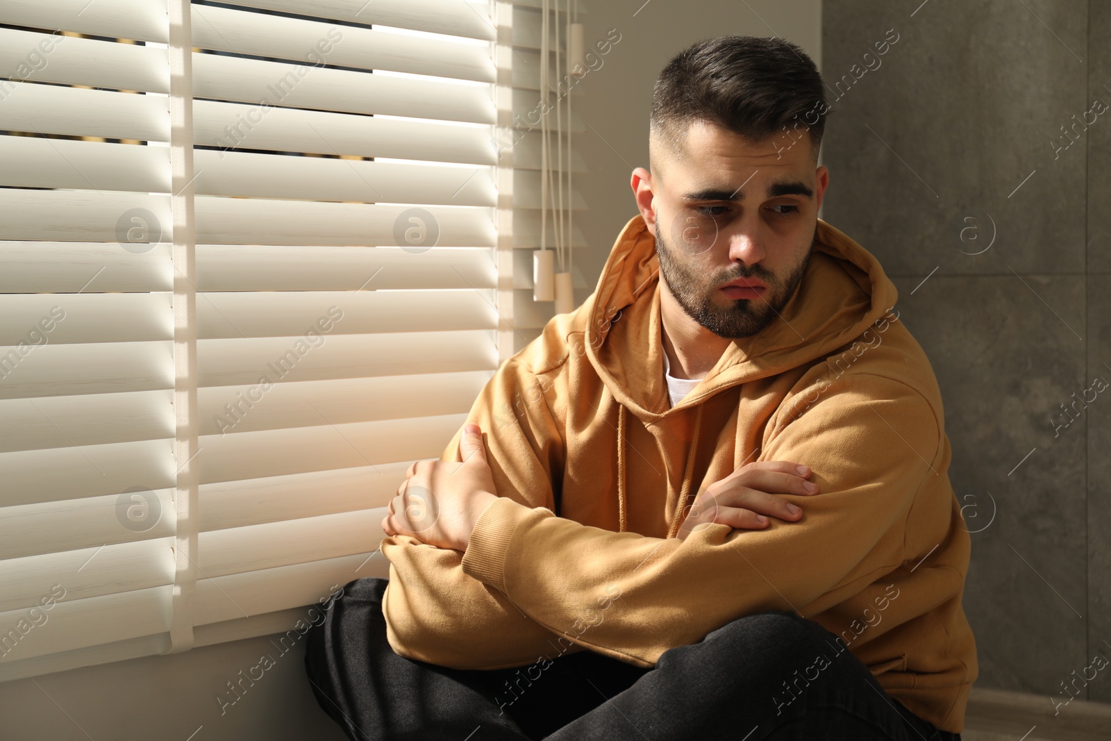 Photo of Sad young man and sitting near window