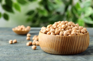 Photo of Raw chickpeas in bowl on blue wooden table. Space for text