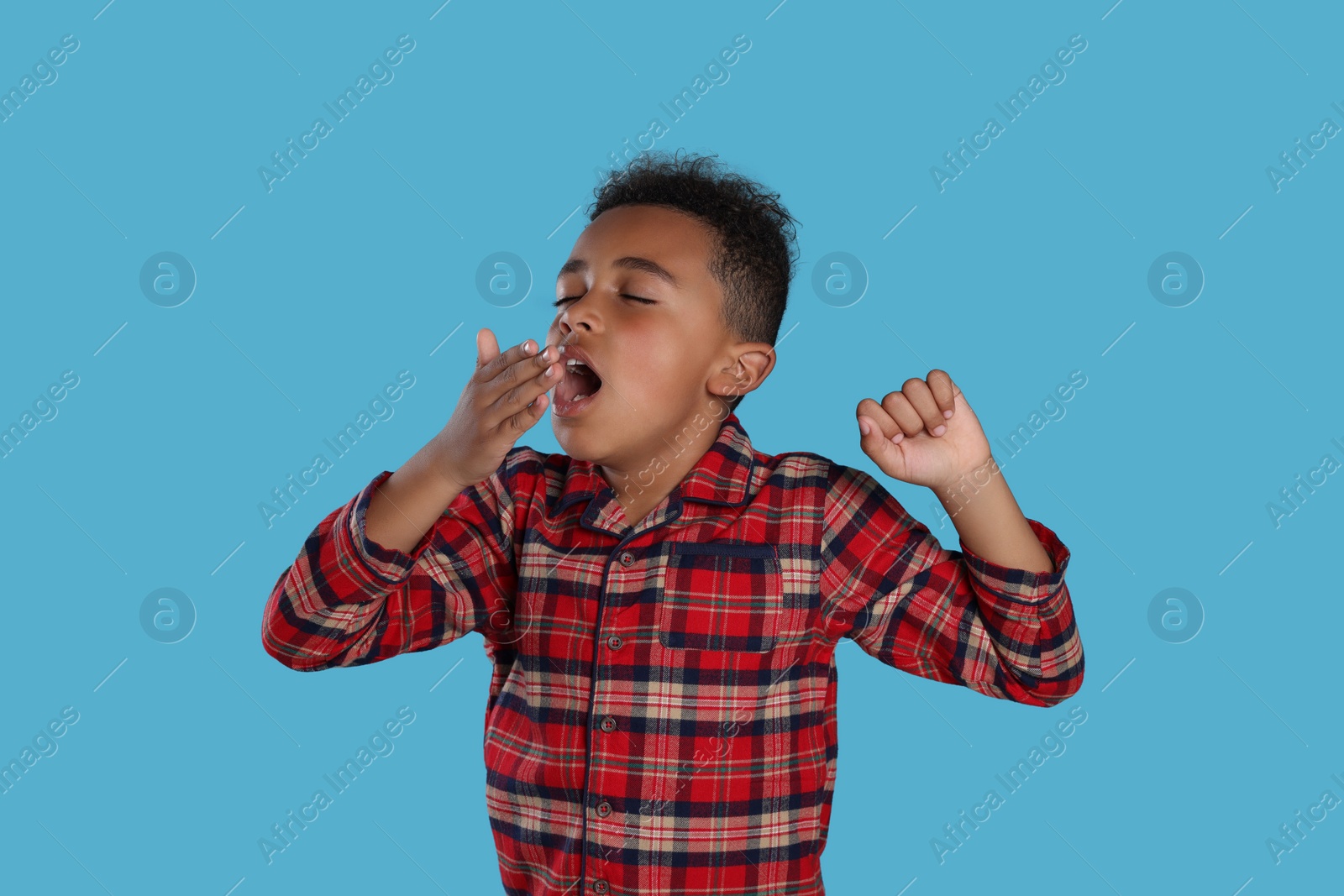 Photo of Boy yawning and stretching on light blue background. Insomnia problem