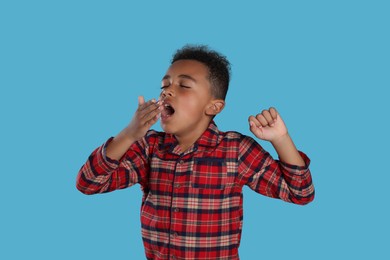 Photo of Boy yawning and stretching on light blue background. Insomnia problem