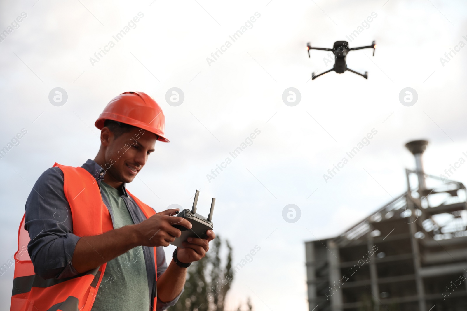 Photo of Builder operating drone with remote control at construction site. Aerial survey