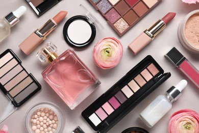 Photo of Flat lay composition with different makeup products and beautiful spring flowers on grey background