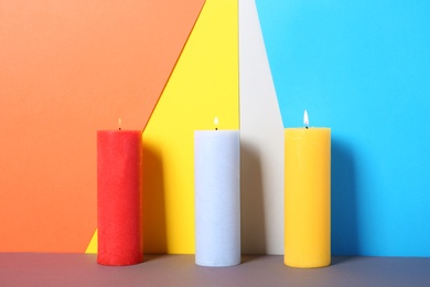 Decorative candles on table against color background