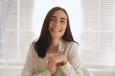 Photo of Young woman talking to her coworkers through video conference indoors, view from webcam