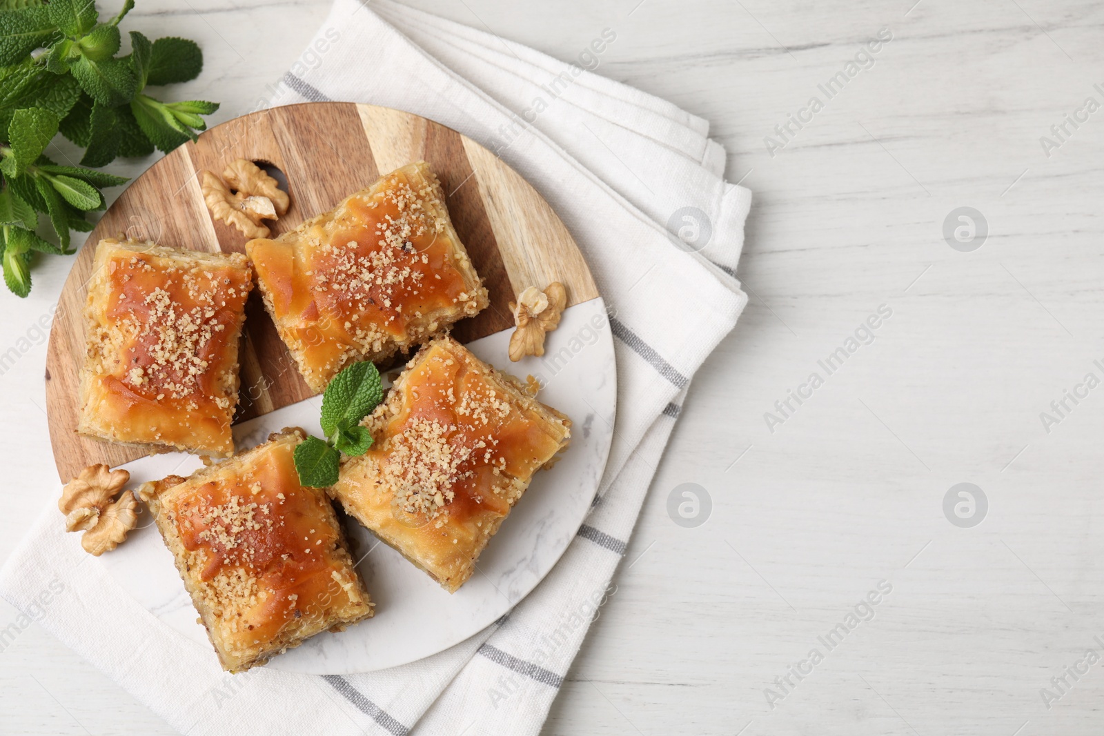 Photo of Eastern sweets. Pieces of tasty baklava on white wooden table, top view. Space for text