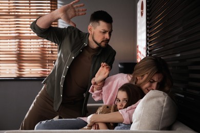 Photo of Man abusing his wife and daughter at home. Domestic violence