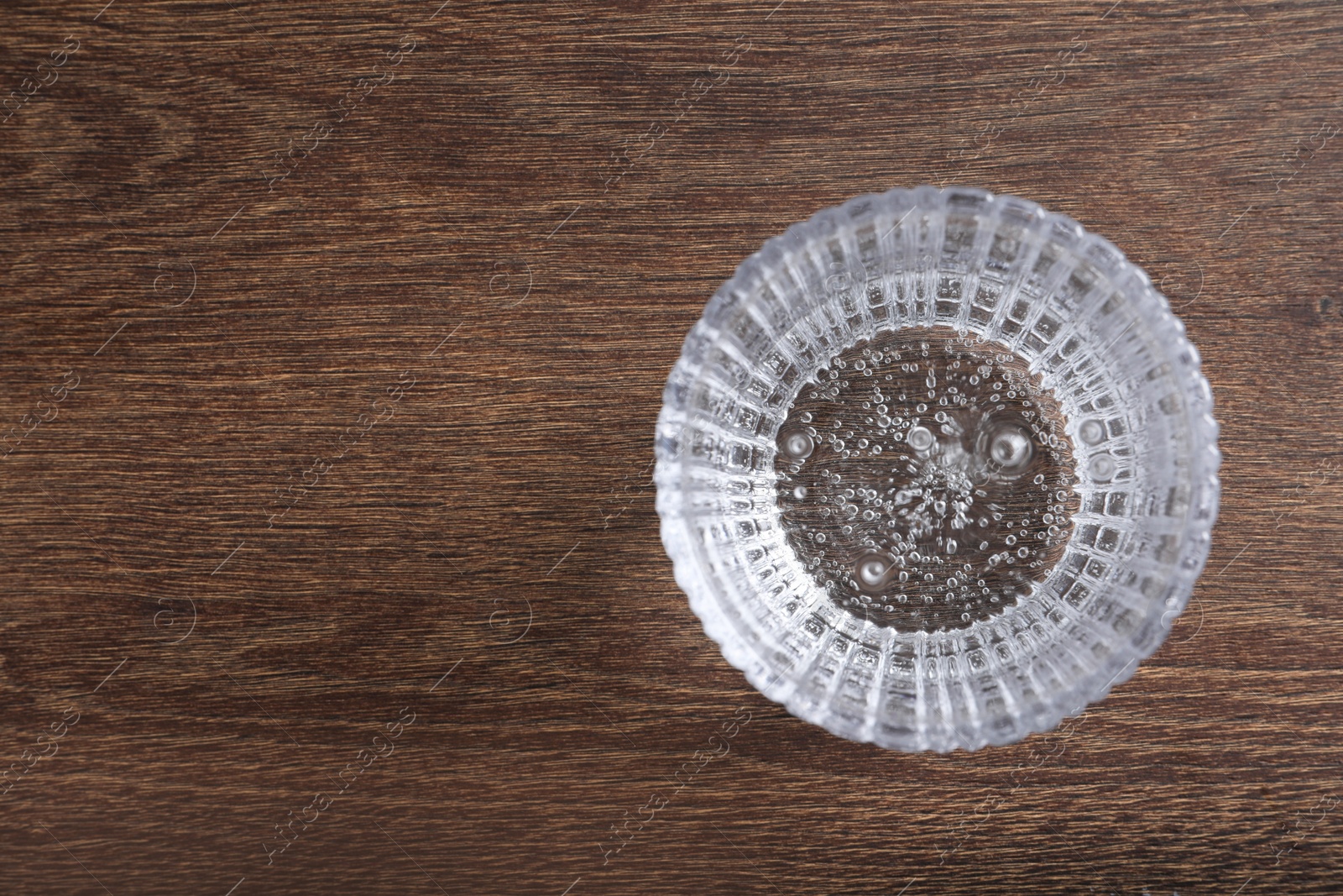 Photo of Glass of soda water on wooden table, top view. Space for text