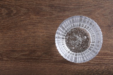 Photo of Glass of soda water on wooden table, top view. Space for text