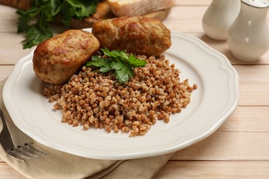 Photo of Tasty buckwheat with fresh parsley, cutlets and fork on wooden table, closeup