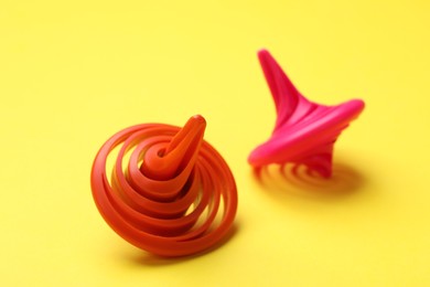 Photo of Red and pink spinning tops on yellow background, closeup
