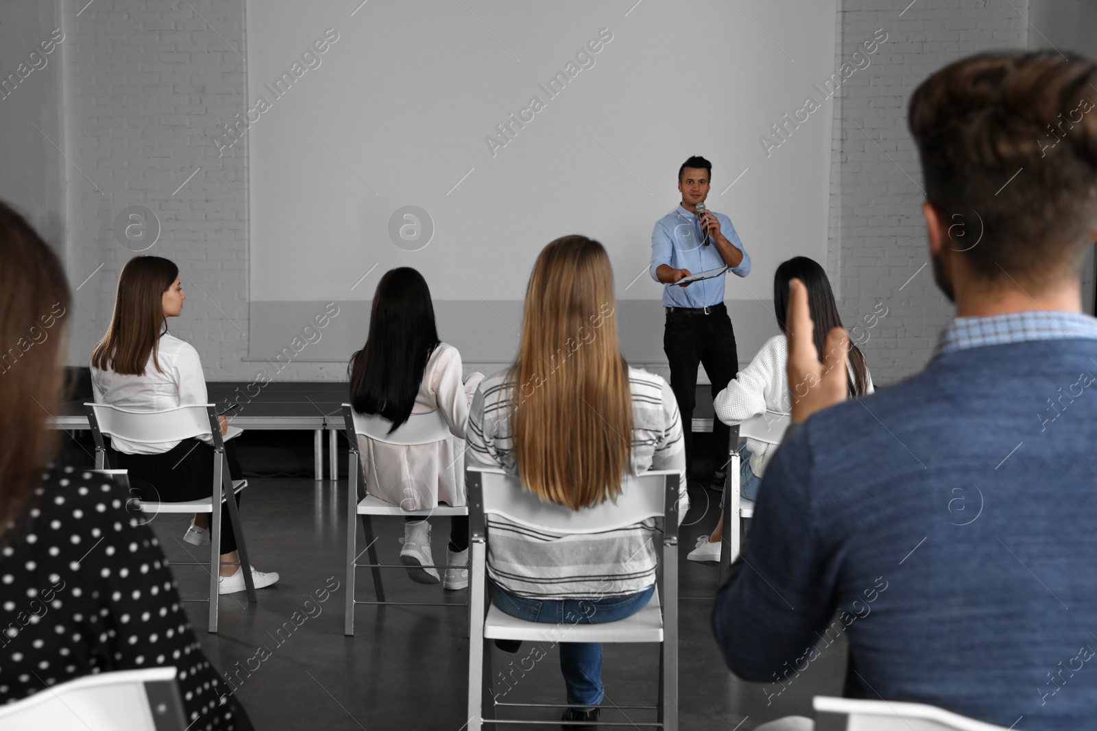 Photo of Male business trainer giving lecture in conference room with projection screen