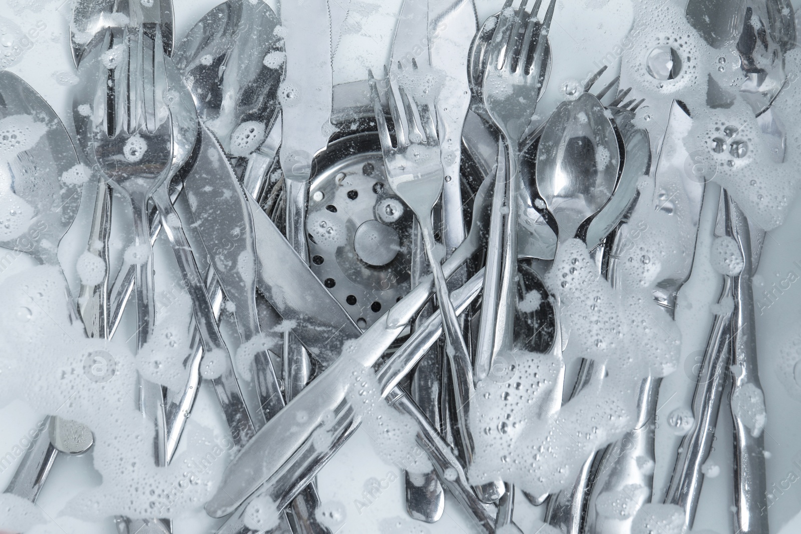 Photo of Washing silver spoons, forks and knives in kitchen sink with foam, flat lay