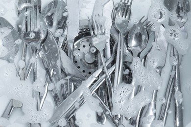 Photo of Washing silver spoons, forks and knives in kitchen sink with foam, flat lay
