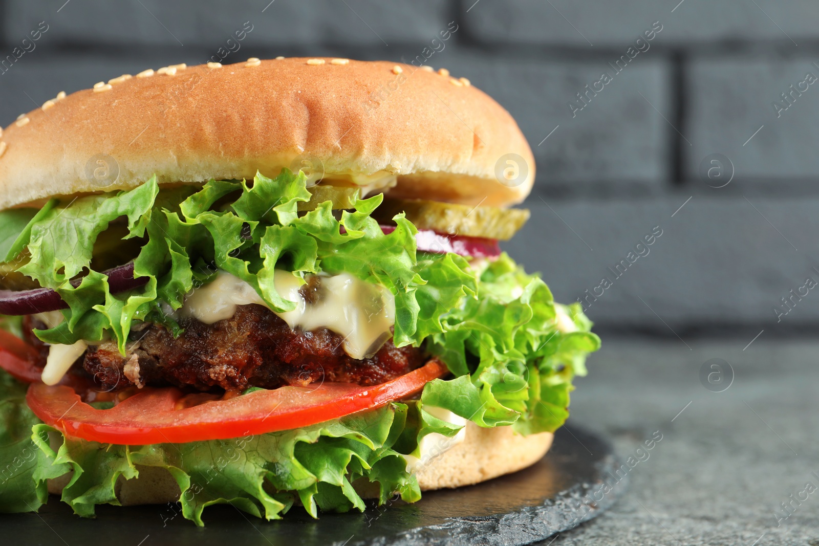 Photo of Delicious burger with beef patty and lettuce on light grey table, closeup