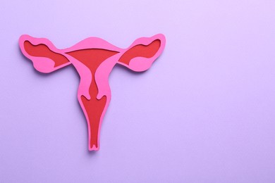 Photo of Reproductive medicine. Paper uterus on violet background, top view with space for text