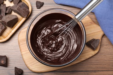 Photo of Delicious chocolate cream and whisk in glass bowl on wooden table, flat lay