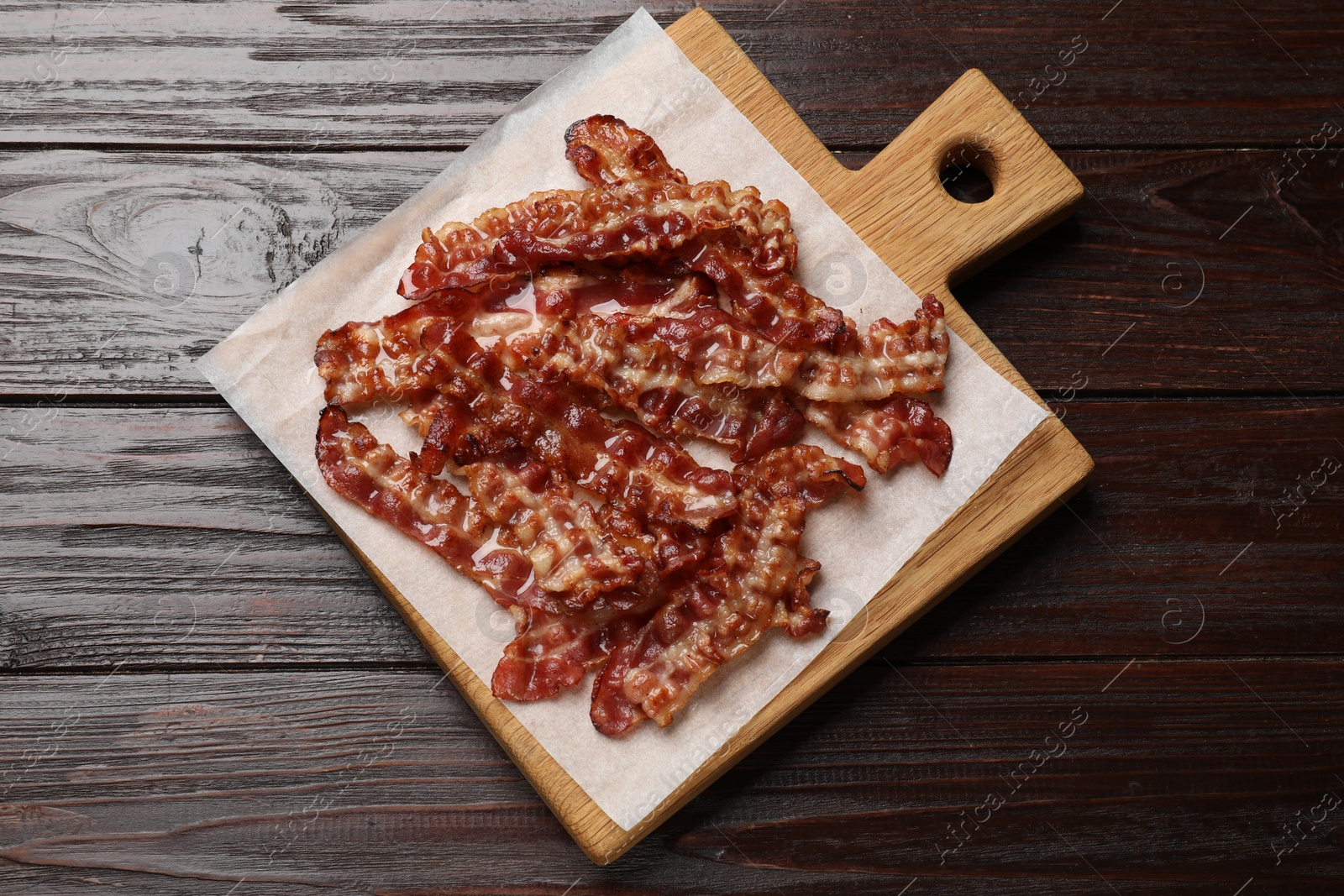 Photo of Slices of tasty fried bacon on wooden table, top view