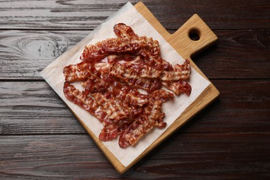 Photo of Slices of tasty fried bacon on wooden table, top view