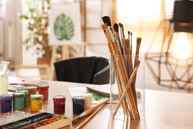 Paints and brushes on wooden table in art studio