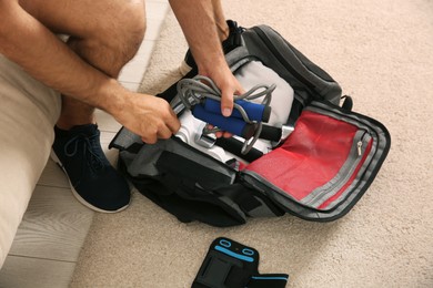 Man packing sports stuff for training into bag indoors, closeup