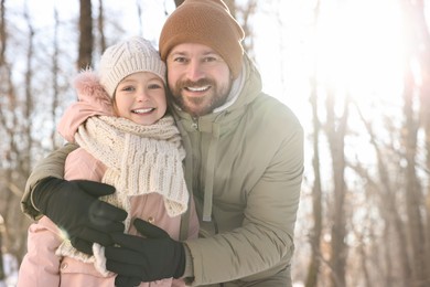 Family portrait of happy father and his daughter in sunny snowy forest. Space for text