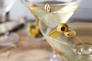 Photo of Glasses of Classic Dry Martini with olives on wooden table against grey background, closeup