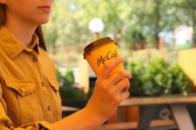 Photo of MYKOLAIV, UKRAINE - AUGUST 11, 2021: Woman with hot McDonald's drink in outdoor cafe, closeup