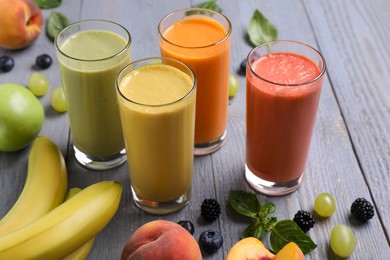 Photo of Many different delicious smoothies and ingredients on grey wooden table