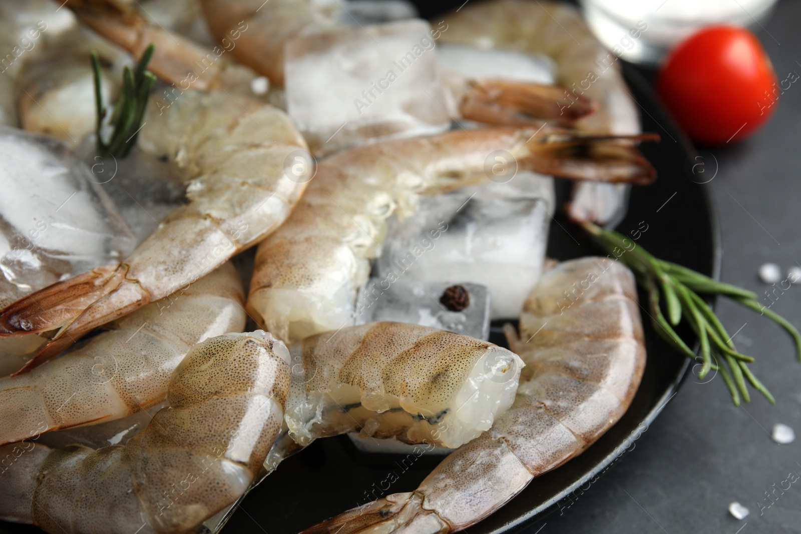 Photo of Fresh raw shrimps with rosemary and ice cubes on plate, closeup