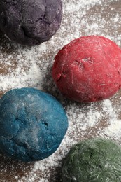 Photo of Dough painted with food colorings on wooden table, flat lay