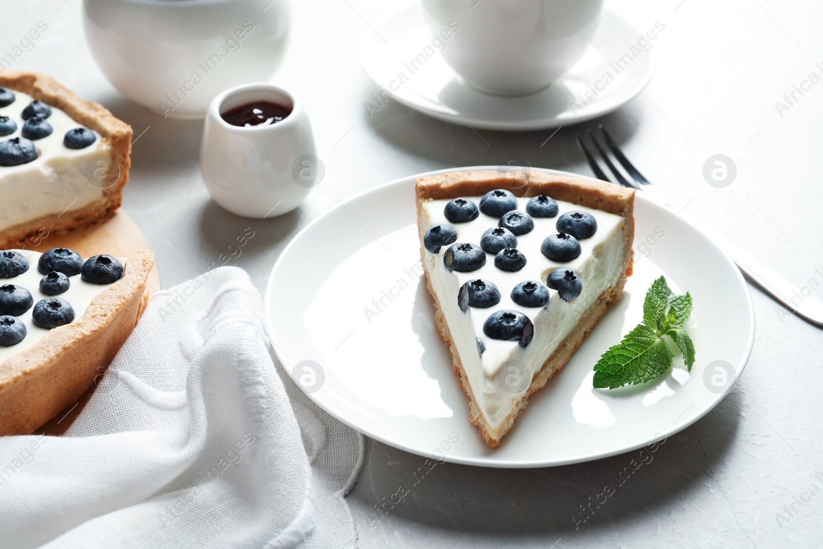 Photo of Plate with piece of tasty blueberry cake on gray table