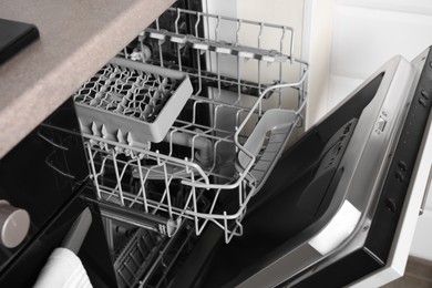 Photo of Open clean empty dishwasher in kitchen, closeup