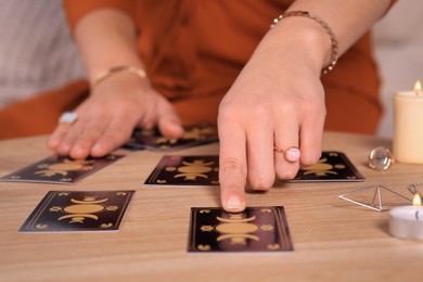 Photo of Soothsayer predicting future with tarot cards at table indoors, closeup