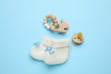Knitted baby booties and accessories on turquoise background, flat lay