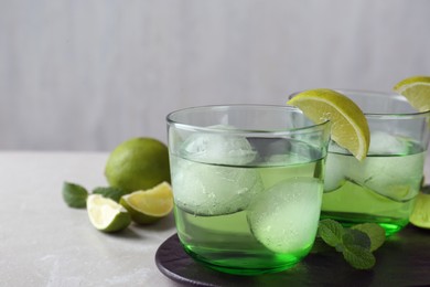 Delicious cocktails with lime and ice balls on grey table, space for text