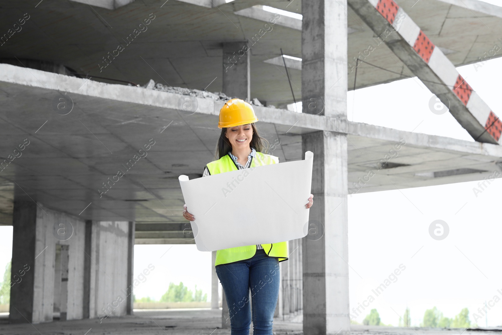 Photo of Professional engineer in safety equipment with drafting at construction site