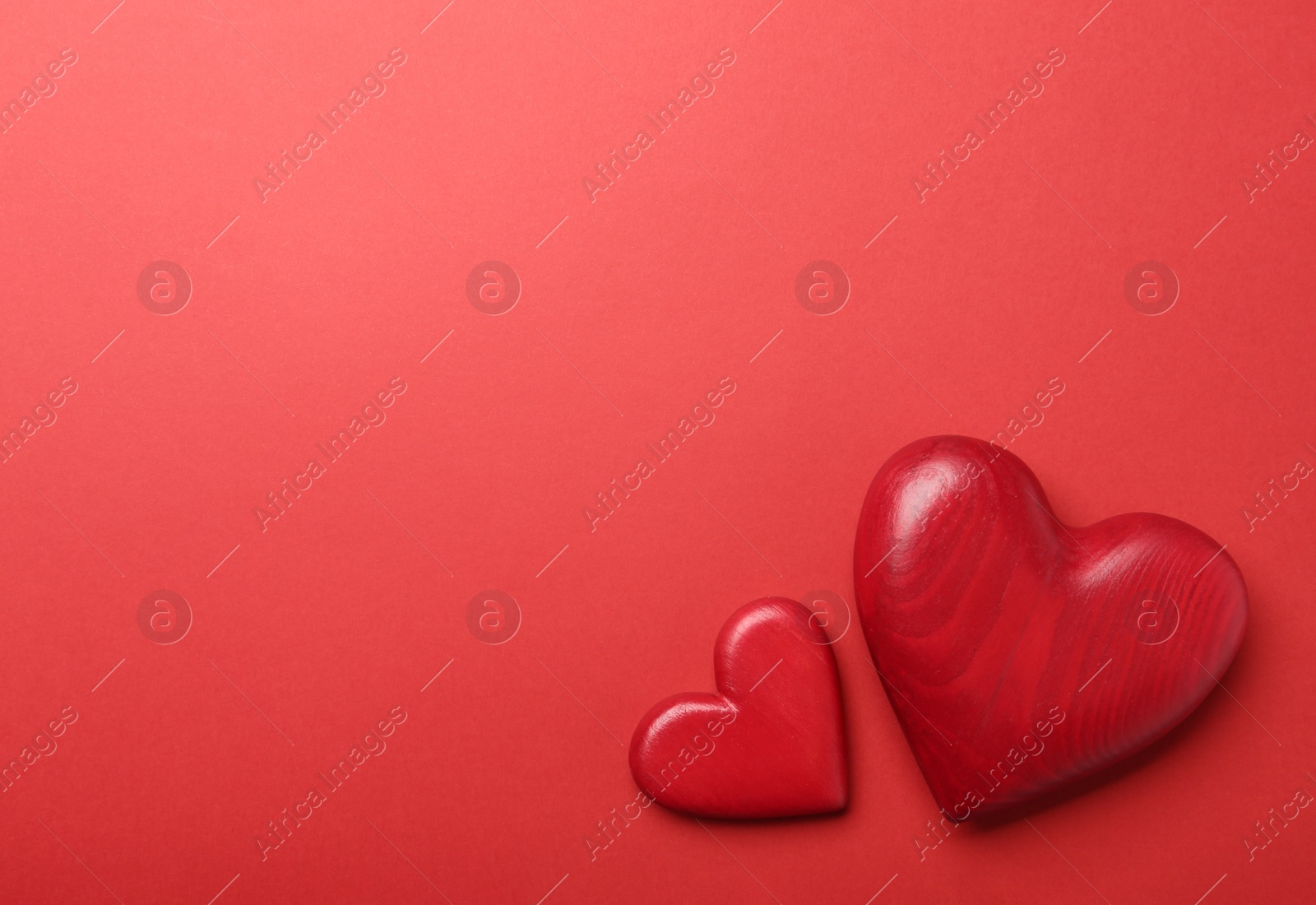 Photo of Decorative wooden hearts on red background, flat lay. Space for text
