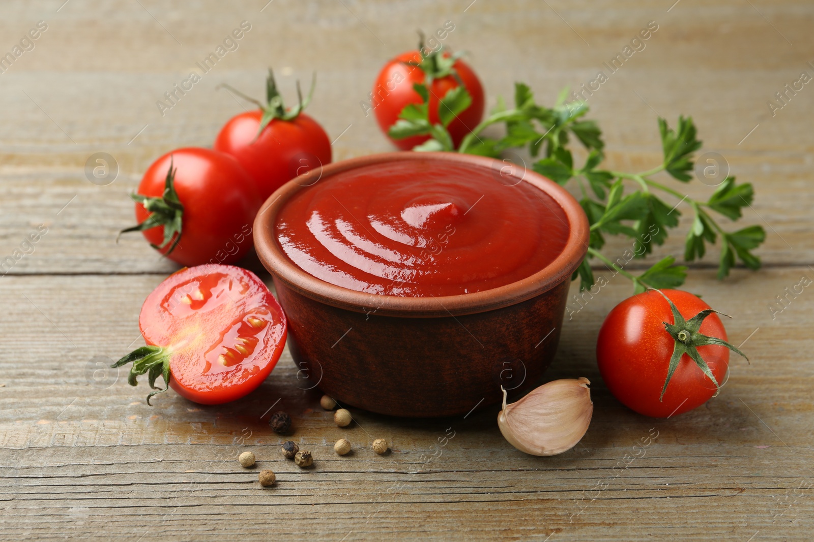 Photo of Tasty ketchup, fresh tomatoes, parsley and spices on wooden table