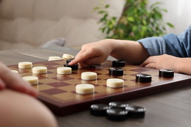 Photo of Children playing checkers at table in room, closeup