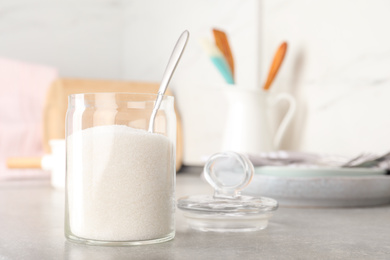 Jar with white sugar on grey table