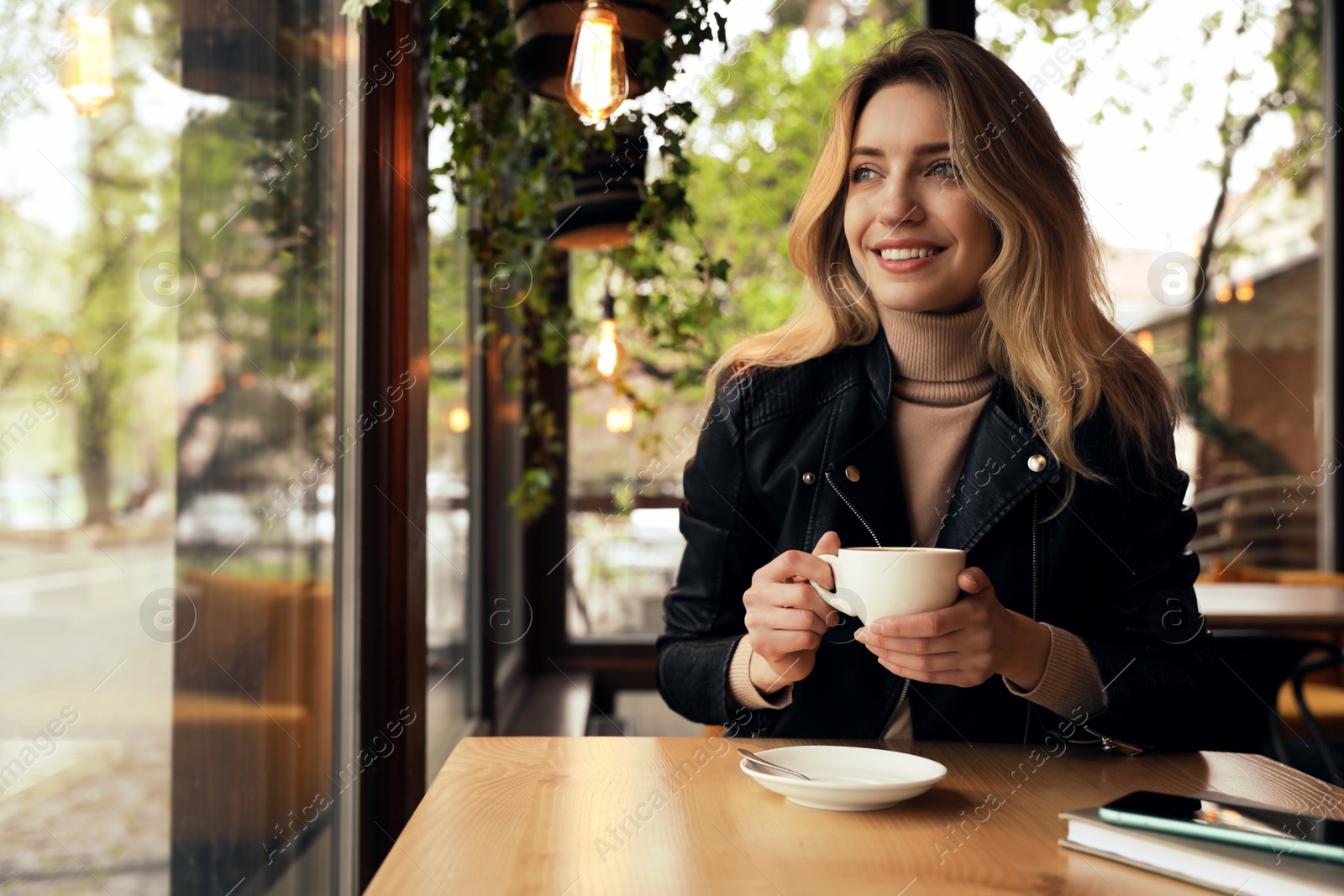 Photo of Young woman with cup of coffee at cafe in morning