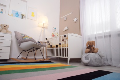 Cozy baby room interior with crib and rocking chair