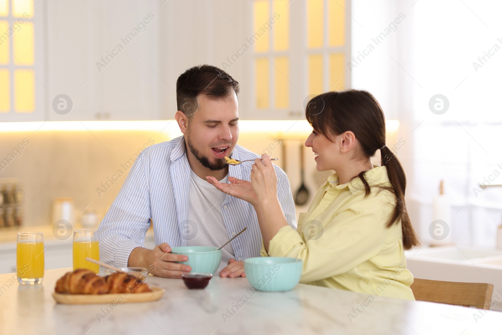 Photo of Tasty breakfast. Happy wife feeding her husband at home